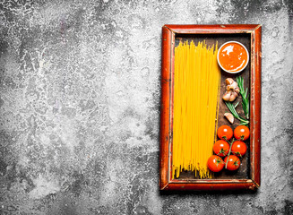 Pasta background. Spaghetti with sauce and tomatoes in the old tray.