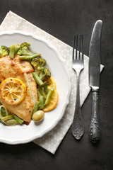 Plate with delicious chicken fillet and sliced lemon on table