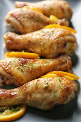 Delicious roasted chicken drumsticks with lemon on plate, closeup