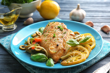 Plate with delicious roasted chicken fillet and sliced lemon on wooden table