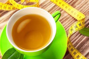 Cup of tea and measuring tape on wooden table. Weight loss concept