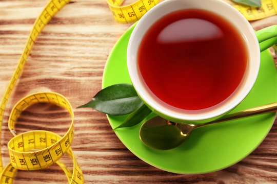 Cup of tea and measuring tape on wooden table. Weight loss concept