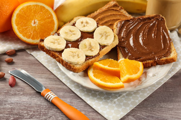 Different tasty sandwiches with peanut butter and fruits on plate