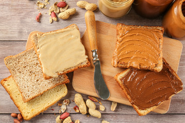 Tasty sandwiches with peanut butter on wooden board