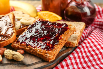 Tasty sandwiches with peanut butter and jam on table
