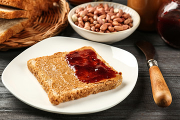 Tasty sandwich with peanut butter and jam on table