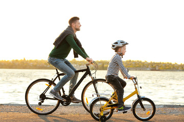 Obraz premium Dad and son riding bicycles near water front