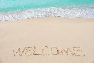 Word WELCOME on beach sand. Summer vacation concept