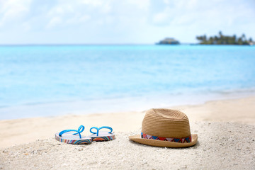 Obraz premium Flip-flops and hat on sea beach. Summer vacation concept