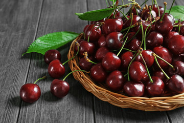 Wicker plate with fresh sweet cherries on table