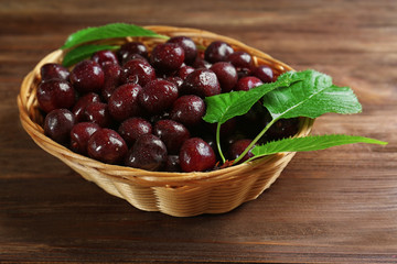 Wicker bowl with fresh ripe cherries on table