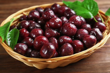 Wicker bowl with fresh ripe cherries on table