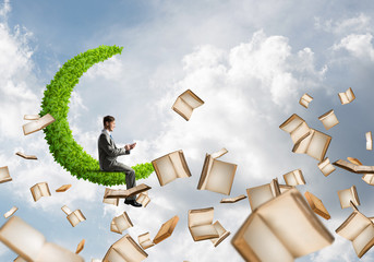 Man using smartphone and many books flying in air