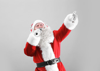 Santa Claus singing Christmas songs on light background