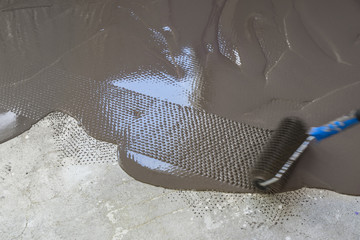 Spreading self leveling plaster with a special roller. Interior