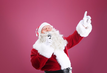 Santa Claus singing Christmas songs on color background