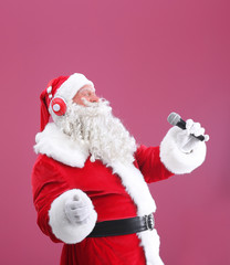 Santa Claus singing Christmas songs on color background