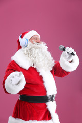 Santa Claus singing Christmas songs on color background