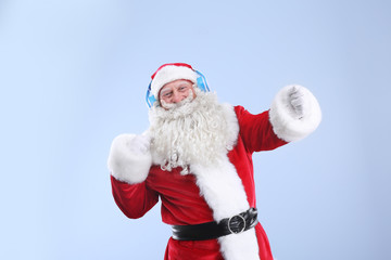 Santa Claus listening to music on color background