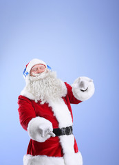 Fototapeta na wymiar Santa Claus listening to music on color background