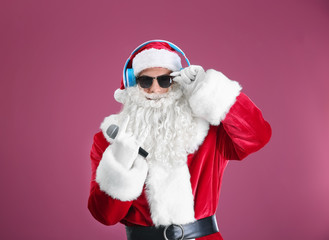 Santa Claus singing Christmas songs on color background