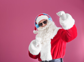 Santa Claus listening to music on color background