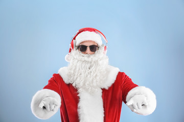 Santa Claus listening to music on color background