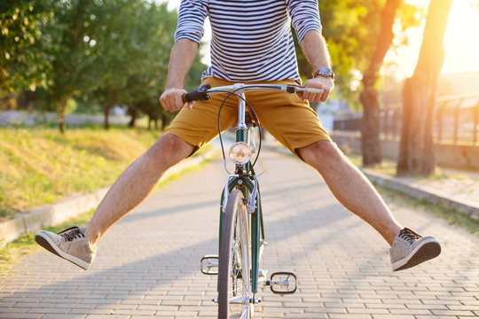 Close up of hipster man riding bicycle with his legs in the air