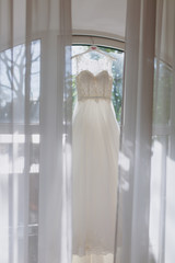 A beautiful wedding dress hanging in a room flooded with sunlight