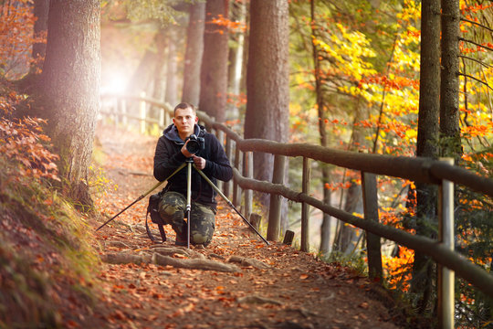 photographer in autumn forest witw photo camera