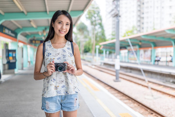 Obraz premium Young asian Woman holding digital camera in light rail station