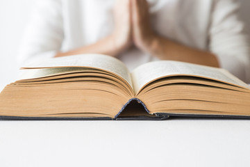 Opened bible in the quiet, light atmosphere. Prayer time on sunday. Woman's hands on the bible.