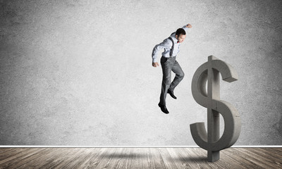 Determined banker man in empty concrete room breaking dollar figure