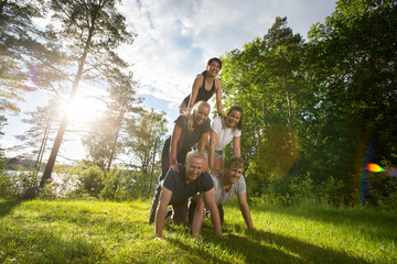 Portrait Of Happy Friends Making Human Pyramid On Field