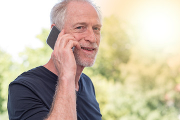 Portrait of smiling mature man talking on phone, light effect