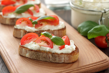Homemade italian sandwich bruschetta with tomatoes, feta and basil on cutting board.