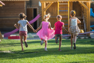 friendship. Four little girls run to play on the playground. Taken from the back Kids run to play