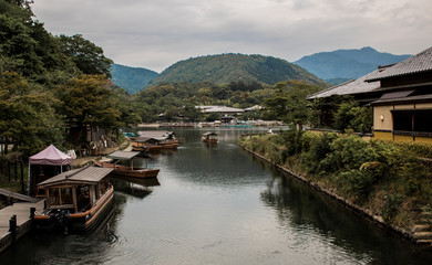 Fototapeta na wymiar Beautiful Japanese scenery with a river, blue misty mountains and canal boats