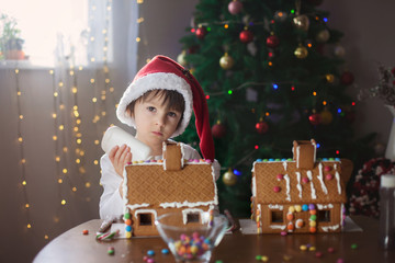 Obraz na płótnie Canvas Cute little boy, making gingerbread cookies house for Christmas