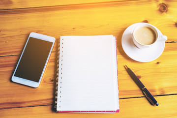 on wooden table in  coffee shop interior near mobile phone and cup of  coffee  book pen and smartphone , blank space on book