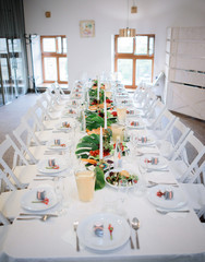 Long dinner table served with plates with salad and greenery