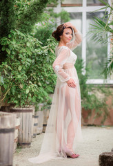 Elegant lady in white lace robe poses in the garden