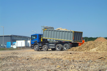 Obraz premium Dump truck unloading soil on construction site