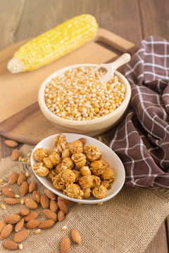 Corn kernels in wooden plates and popcorn with Caramel and almond cream on wooden table