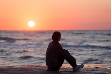 Lonely girl sitting on the sunrise beach - 168168942