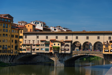 Fototapeta na wymiar River Arno and famous bridge Ponte Vecchio (The Old Bridge) at sunny summer day. Florence, Tuscany, Italy