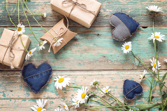 Rural background with daisies, decorative hearts and gift boxes.