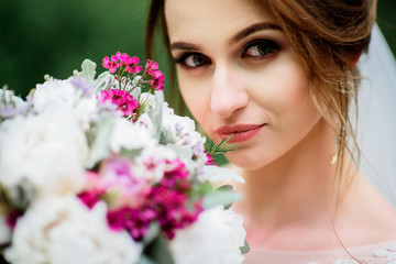 Bride holds beautiful wedding bouquet before her face