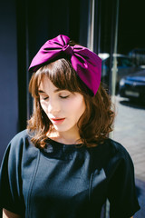 Beautiful woman in a dark stylish dress strolls along the street, near boutiques. Portrait of a fashionable girl