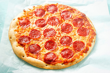 Pizza with cheese and pepperoni on blue surface